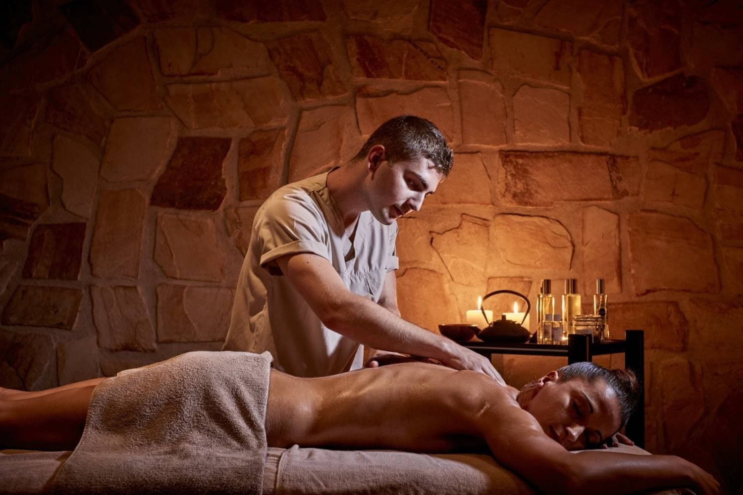 Massage therapist performing a back massage in a stone-walled treatment room at Zoe Spa Mykonos
