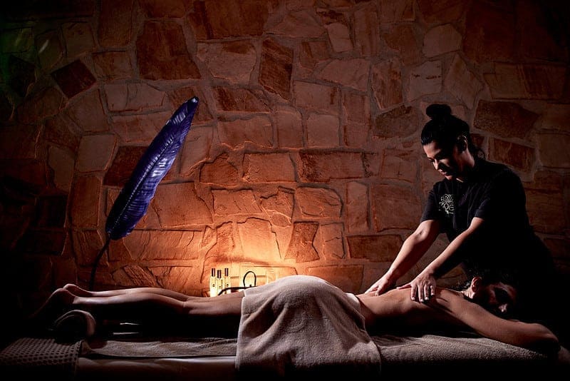 Massage therapist treating a guest's back in a stone treatment room at Zoe Spa Mykonos