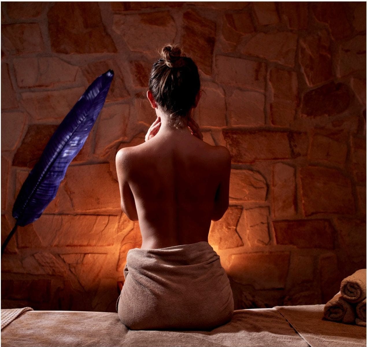 Guest seated on a massage table before a stone wall at Zoe Spa Mykonos